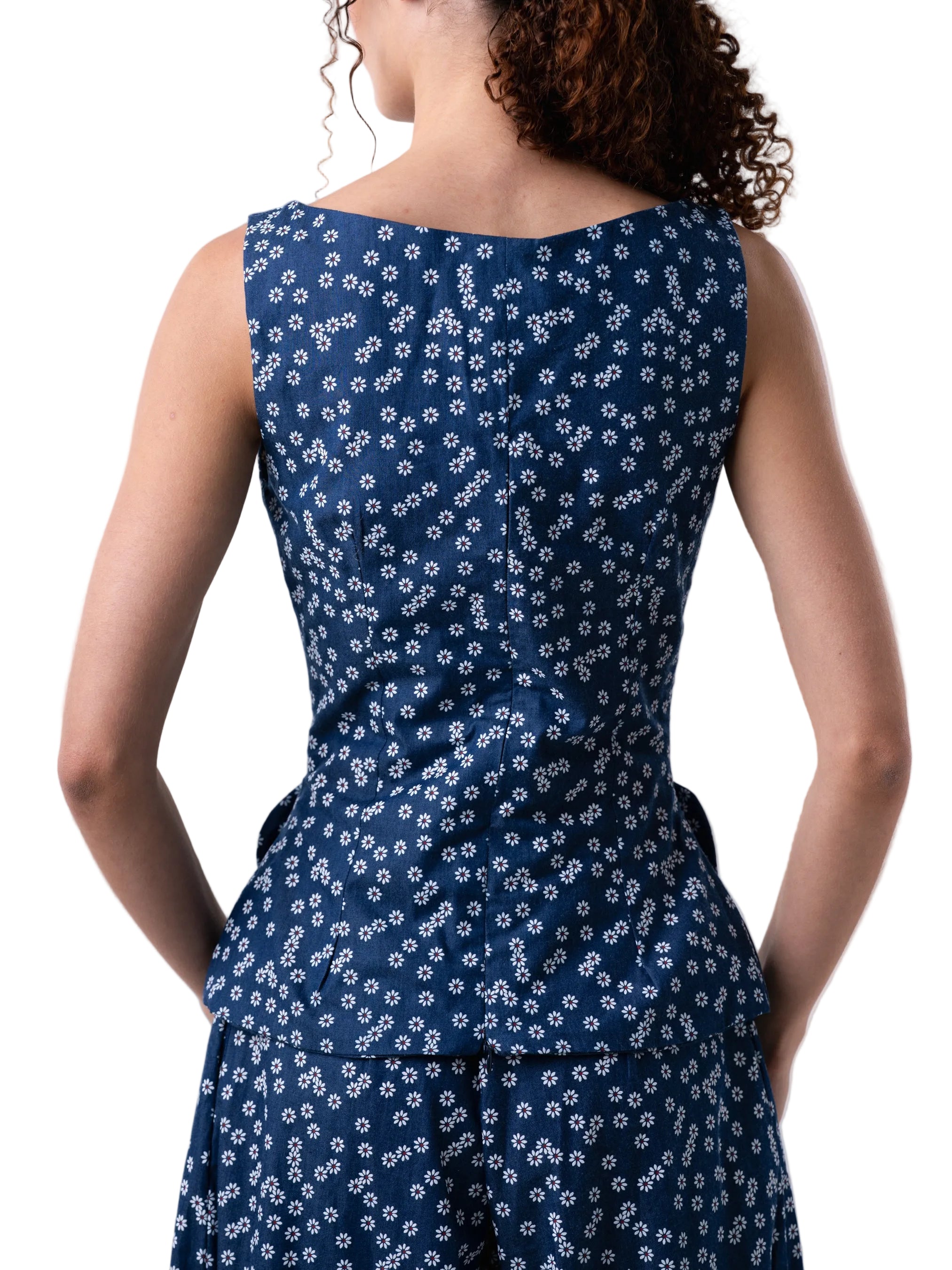 Blue sleeveless vest like top, with fitted silhouette, petal knot detail and back sipper closure.