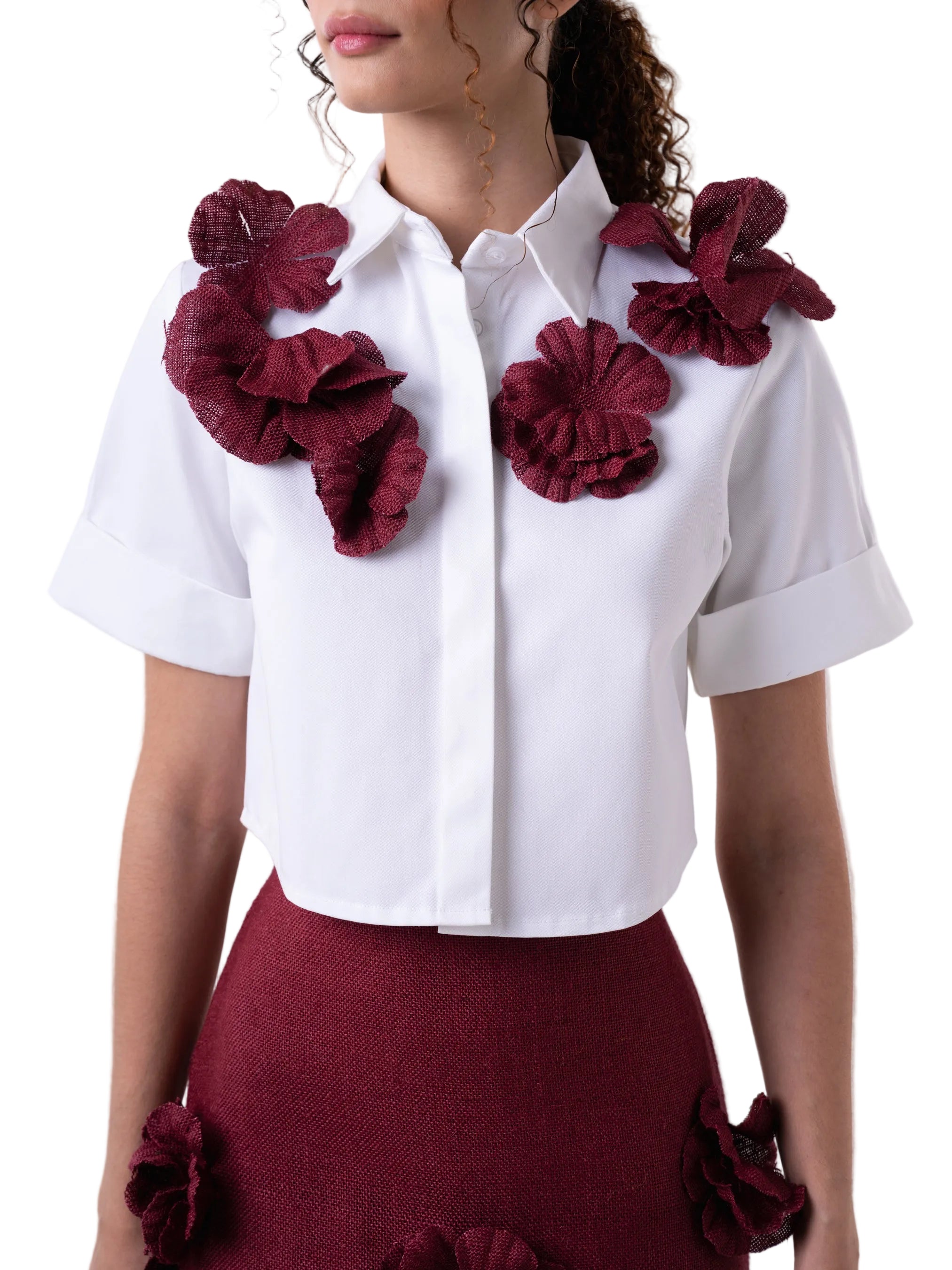 Top that features a classic button down with short sleeves and cuff detail, elevated by hand sewn artisanal jute flowers.