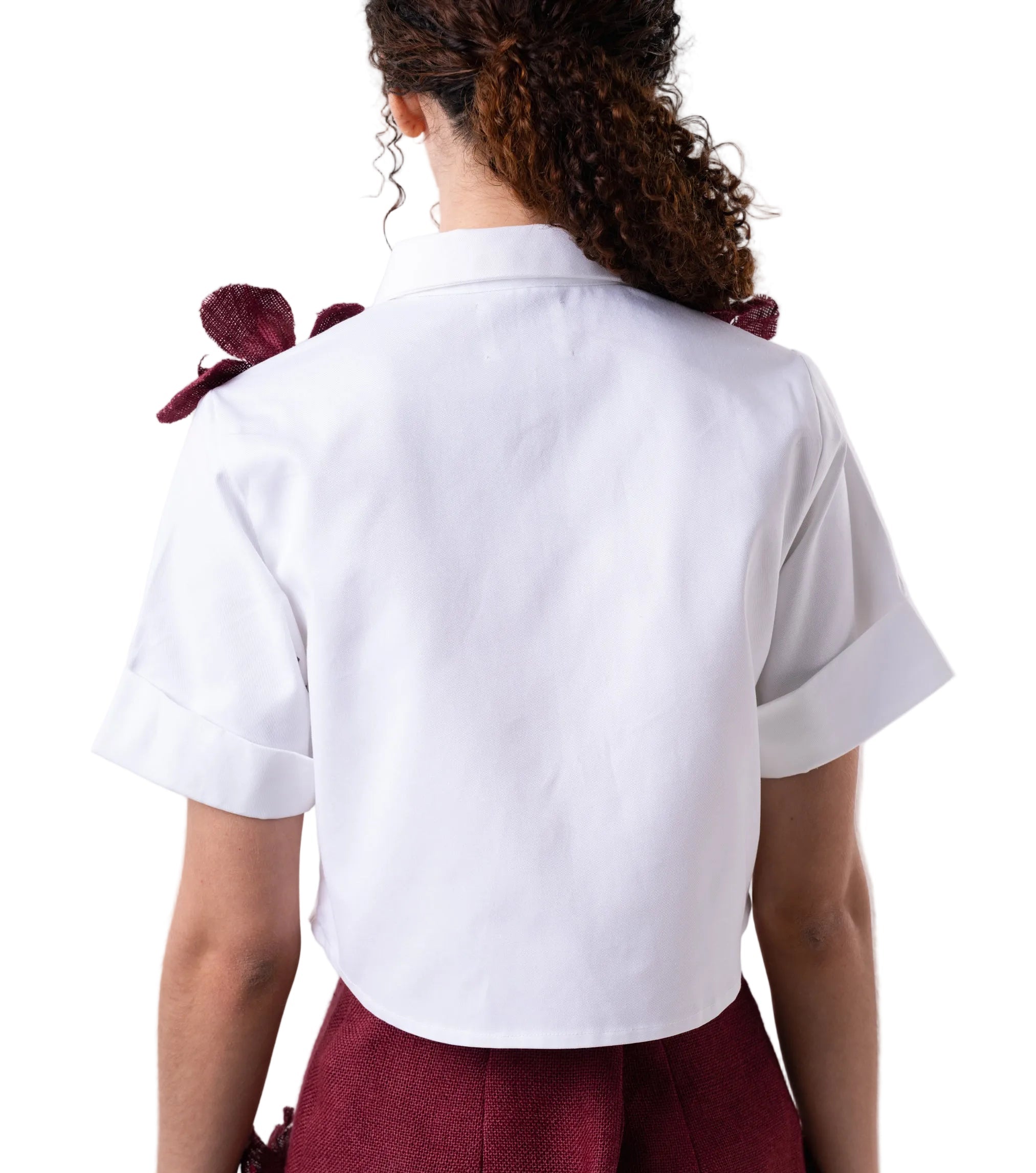 Top that features a classic button down with short sleeves and cuff detail, elevated by hand sewn artisanal jute flowers.