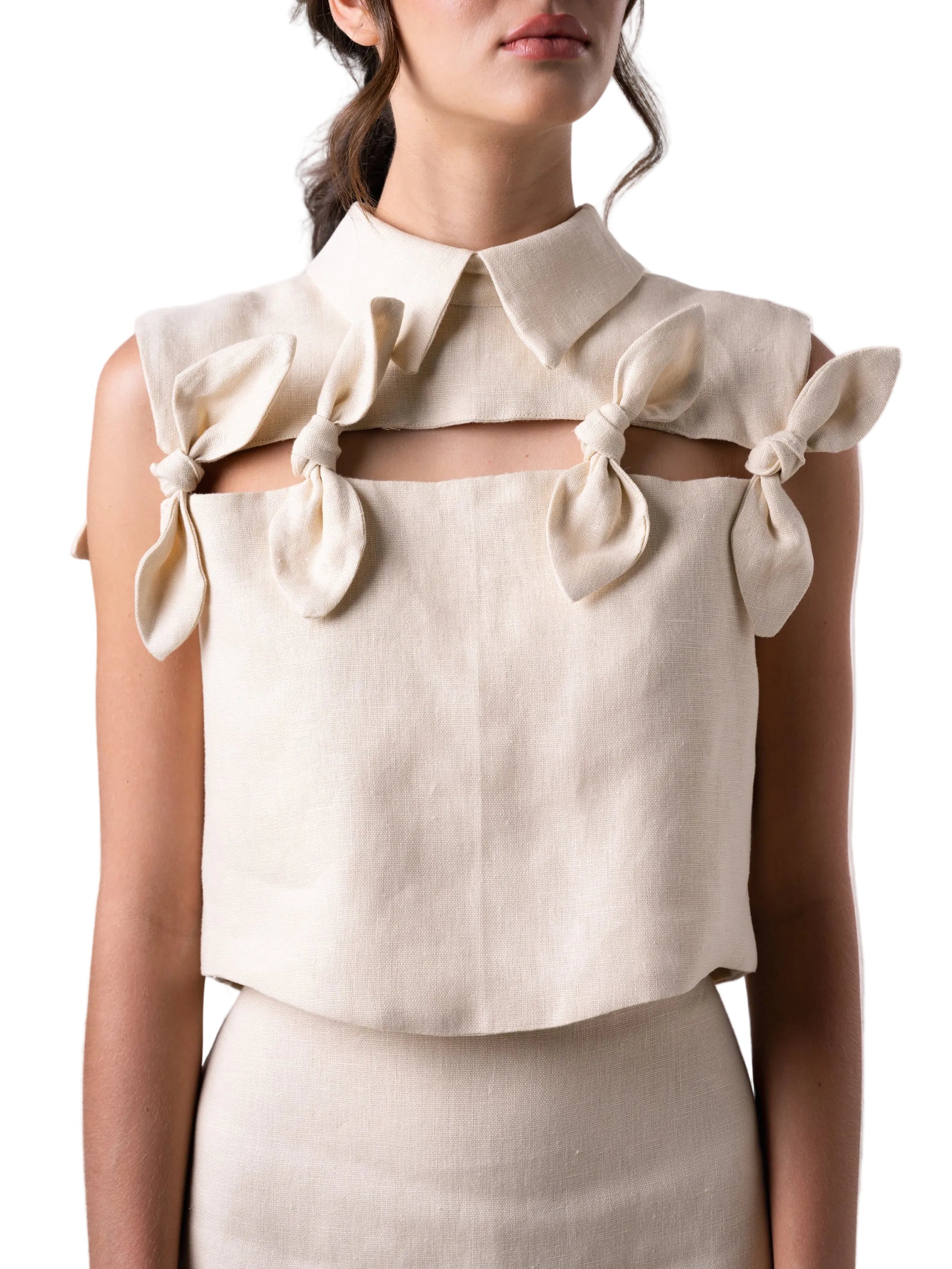 Top with a cropped boxy silhouette, classic collar, cut out detail accentuated with petal knot details, and back button down closure.