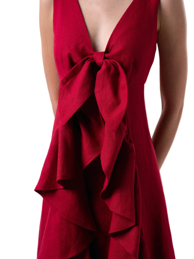 Top that features a sleeveless V neck cut with exaggerated train with ruffle detail.