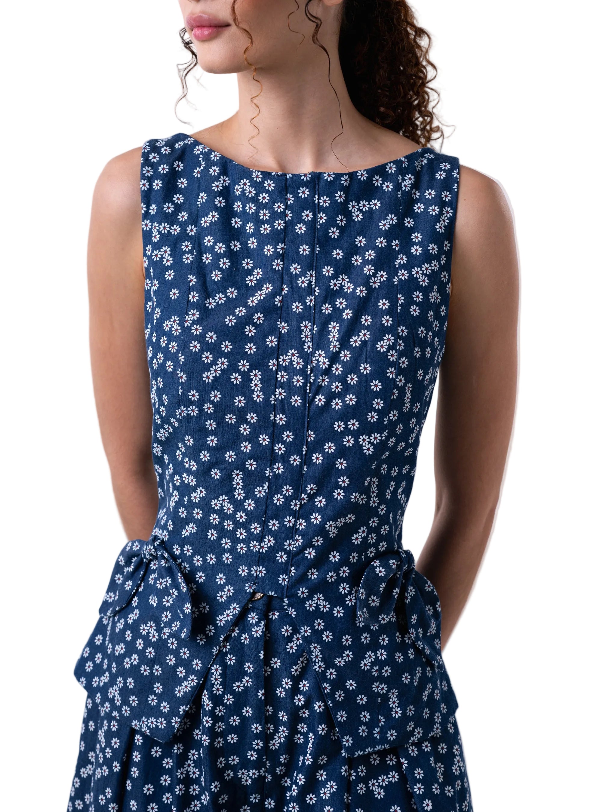 Blue sleeveless vest like top, with fitted silhouette, petal knot detail and back sipper closure.