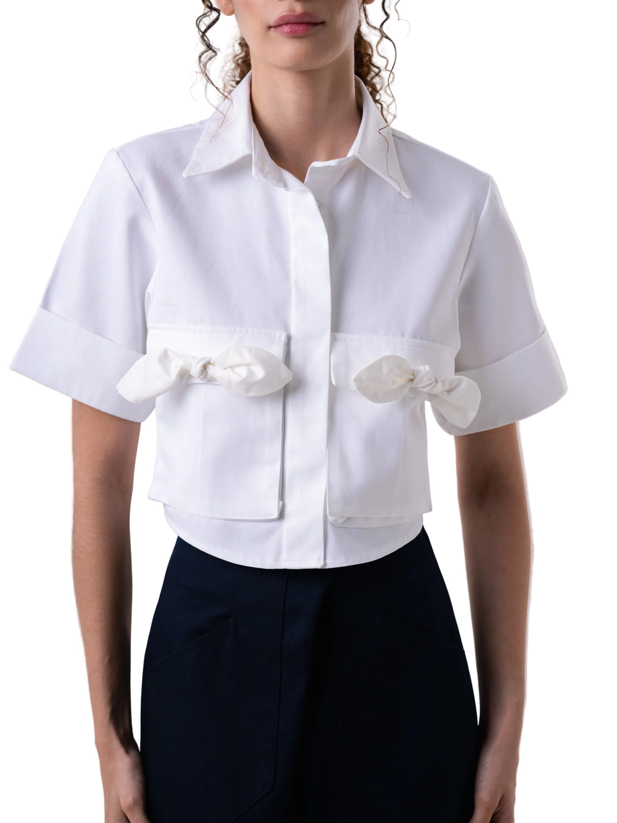 Top that features cropped short sleeve silhouette, classic open collar, sleeve cuff, front button down closure and cargo pockets with petal knot detail.